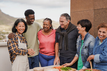Multiracial friends with different ages having fun during rooftop barbecue party
