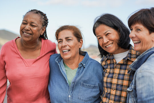 Multiracial senior women having fun hugging each other at house rooftop