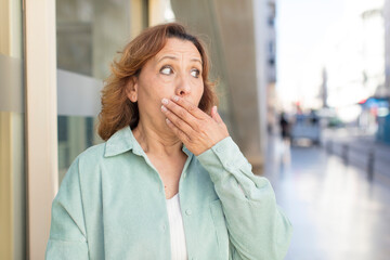 middle age woman covering mouth with hands with a shocked, surprised expression, keeping a secret or saying oops