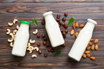 Set or collection of various vegan milk almond, cashew, on table background. Vegan plant based milk and ingredients, top view - obrazy, fototapety, plakaty