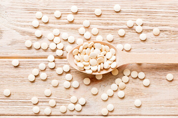 Heap of white pills on colored background. Tablets scattered on a table. Pile of red soft gelatin capsule. Vitamins and dietary supplements concept