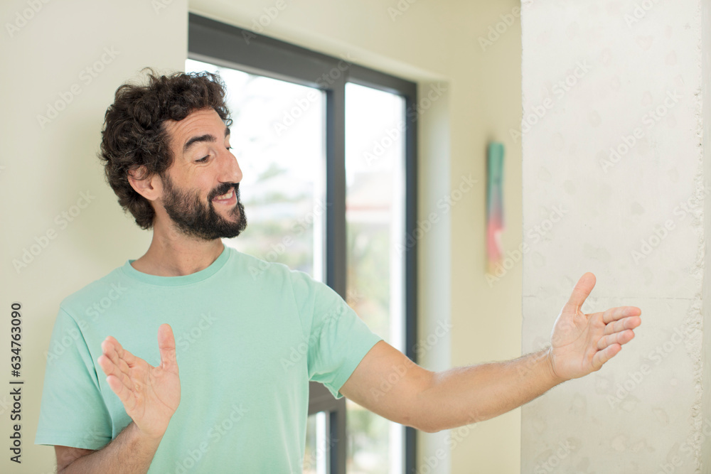 Canvas Prints young crazy bearded man holding an object with both hands on copy space, showing, offering or advertising an object