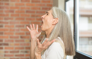 senior pretty woman looking desperate and frustrated, stressed, unhappy and annoyed, shouting and...