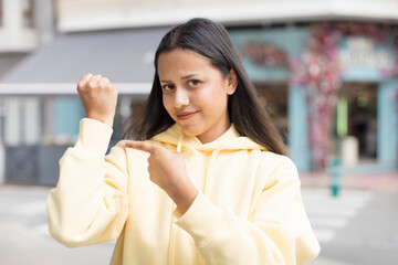 pretty hispanic woman looking impatient and angry, pointing at watch, asking for punctuality, wants...