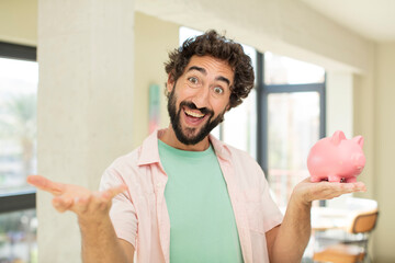 crazy bearded man smiling happily and offering or showing a concept. piggy bank concept