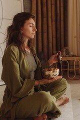 Woman playing on Tibetan singing bowl while sitting on yoga mat. Vintage tonned. Soft focus blurred...