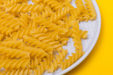 Yellow pasta in the plate on yellow background. 