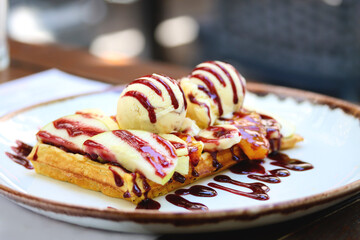 Wholegrain flour belgian waffle with a scoop of ice cream and berry sauce, close up, copy space....