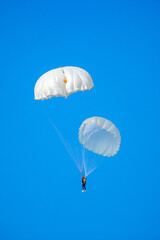 Skydiving. Flying parachutists against the background of the blue sky and mountains. Extreme sport and entertainment.