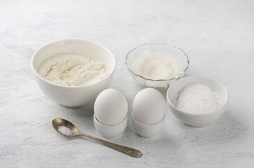 Baking ingredients: flour, sugar, powdered sugar, eggs, salt on a light gray background. Cooking delicious homemade cookies