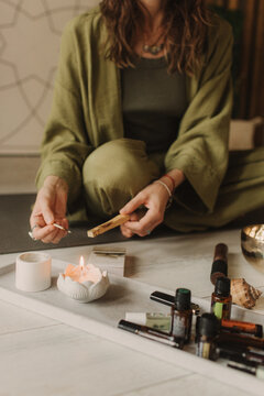 A young woman holds a smoking palo santo stick in her hands. Buddhist healing practices.Clearing the space of negative energy. Aromatherapy. Selective focus,close up. Soft focus and noise effect