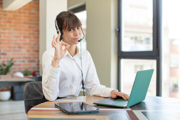 young pretty woman feeling happy, showing approval with okay gesture. telemarketer concept