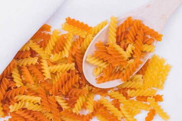 Yellow and orange Fusilli pasta on the tablecloth. Top view.