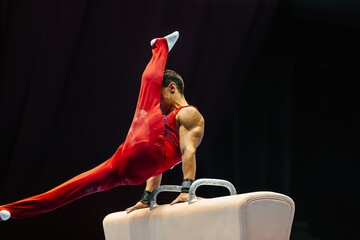 gymnast exercise pommel horse in championship gymnastics, support with hands on horse, swing feet