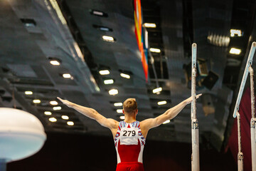 rear view gymnast starting exercise parallel bars in championship gymnastics