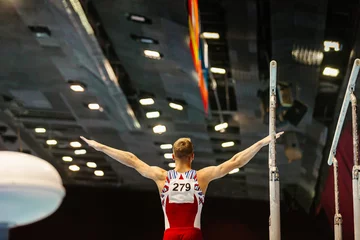Foto op Canvas rear view gymnast starting exercise parallel bars in championship gymnastics © sports photos
