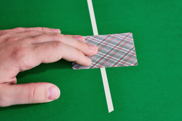 Player's hand is on a playing card on a green table. Make a bet, a decisive move in the game
