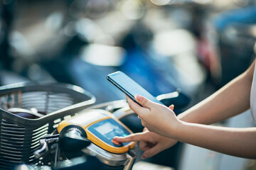 Asian women are utilizing their smartphones to rent shared bicycles for their daily commutes. With...