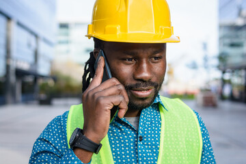 African ethnicity civil engineer man outdoors talking on phone looking down