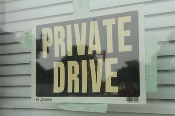 private drive caption text writing sign taped to window with closed blinds behind and reflection in...