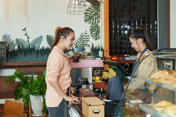 Asian female tourists Become a cafe customer Go in to order drinks and cakes with the beautiful owner at the counter. during a break from walking out of town in a small business shop