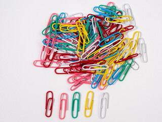 Multicolored paper clips on a white background. Colored paper clips close up.