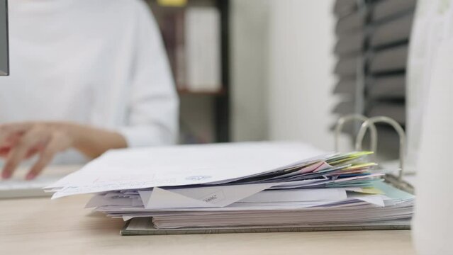 Asian businesswoman working checking financial report for analysis in TAX documents on office desk.