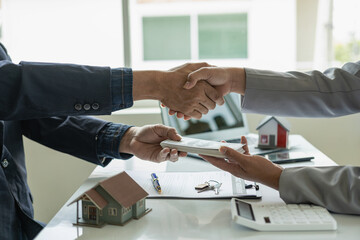 Real estate agents shake hands with clients after entering into a chain agreement for the sale of...