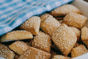 Freshly baked homemade biscuits with sesame covered by towel in bowl.