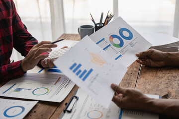 Teamwork with young businessmen analyzes cost graphs on desks at conference rooms. A team of...