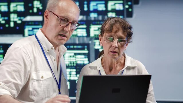 Senescent workers looking around innovative supercomputer hub, preparing to start comission on malfunctioning high tech infrastructure in order to ensure optimum operations