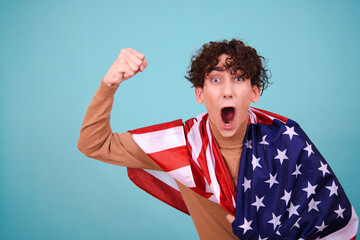 Funny curly guy with the national flag posing in the studio on a blue background.