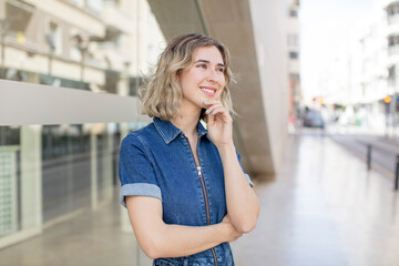 Fototapeta premium pretty woman smiling happily and daydreaming or doubting, looking to the side