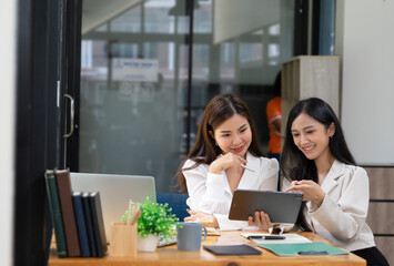 Two happy young women discussing business while working together at the creative office