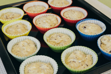 Dough for cupcakes in colorful paper and silicone molds on baking tray. Preparing process to baking. 
