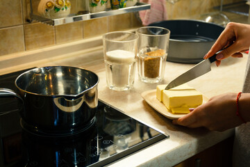 Preparing for cooking, preparing ingredients for cooking on the stove. The moment of cutting butter with a knife.