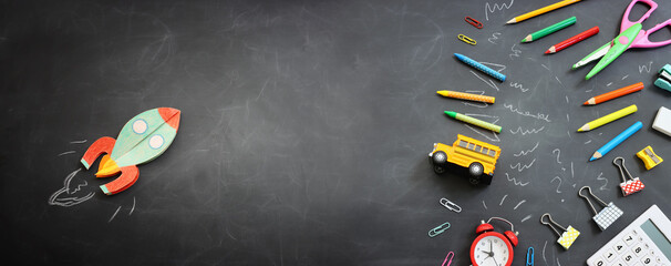 Back to school concept. rocket, bus and pencils over classroom blackboard. Top view