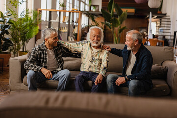 group of senior friends celebrate retirement - diverse generation men hugging at home gathering -