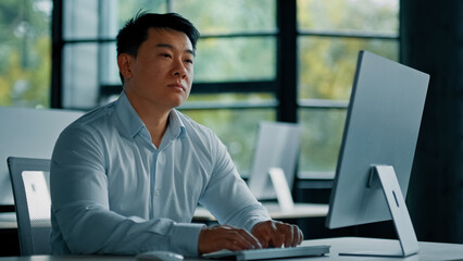 Thoughtful asian korean chinese ceo businessman dreamer smart japanese man guy sit at office desk planning business plan think idea in mind create strategy startup project use computer online work 