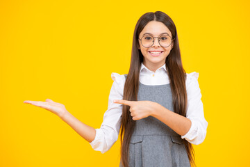 Wow, it's unbelievable. Shocked teenager child pointing aside at copy space. Teen girl pointing with two hands and fingers to the side.
