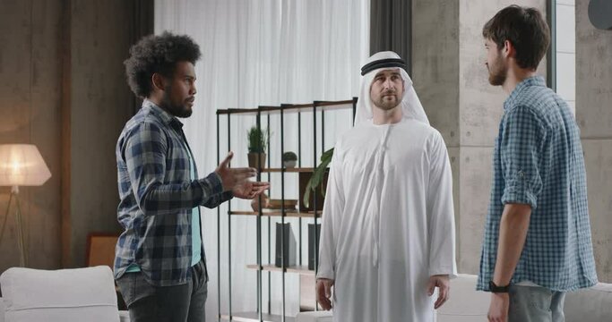 IT startups at business meeting with investor. Two young multi-ethnic IT specialists present their incredible idea to Arab investor. Cultural Community, cross-cultural communication themes concept.