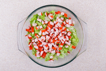 Fresh salad with crab sticks, lettuce and napa cabbage close up in glass bowl . Macro shot. Top view. © andriikomashko