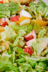 Salad with crab sticks, tomatoes, napa cabbage, eggs, lettuce and croutons close up. Macro shot.