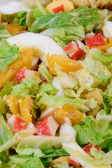 Salad with crab sticks, tomatoes, napa cabbage, eggs, lettuce and croutons close up. Macro shot.