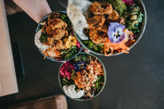 Perspective shot of three different salad bowls held by waiter