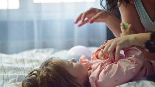 Happy family mother playing with baby on bed in bedroom. Parents have fun with their children spending time together. The concept of a woman's care and love for her daughter. High quality 4k footage