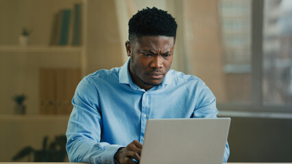 Upset stressed African American man ethnic sad businessman working laptop in home office frustrated...