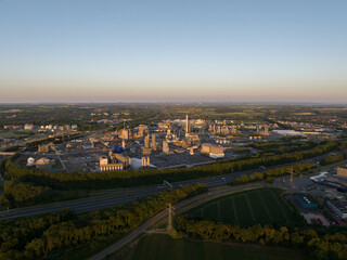 Fototapeta na wymiar Aerial drone view of chemical industrial park at Geleen with a large cooling tower at sunset.