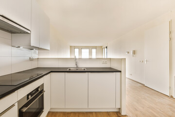 an empty kitchen with white cabinets and black counter tops on the island in front of the sink is also visible
