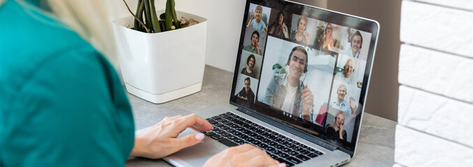 Cropped image of young woman using laptop for video conference at home
